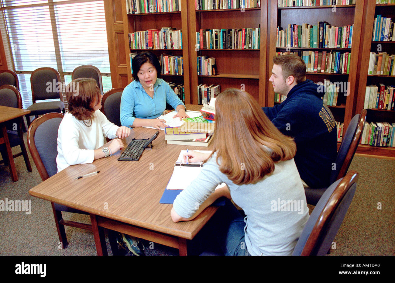 College students work in a group with professor on a research project involving team work Stock Photo