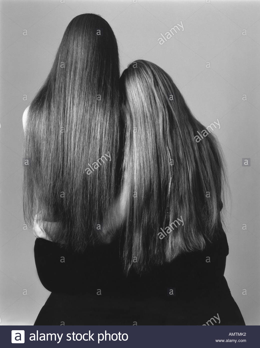 Two Women With Long Hair Side By Side And One Holding Arm Around