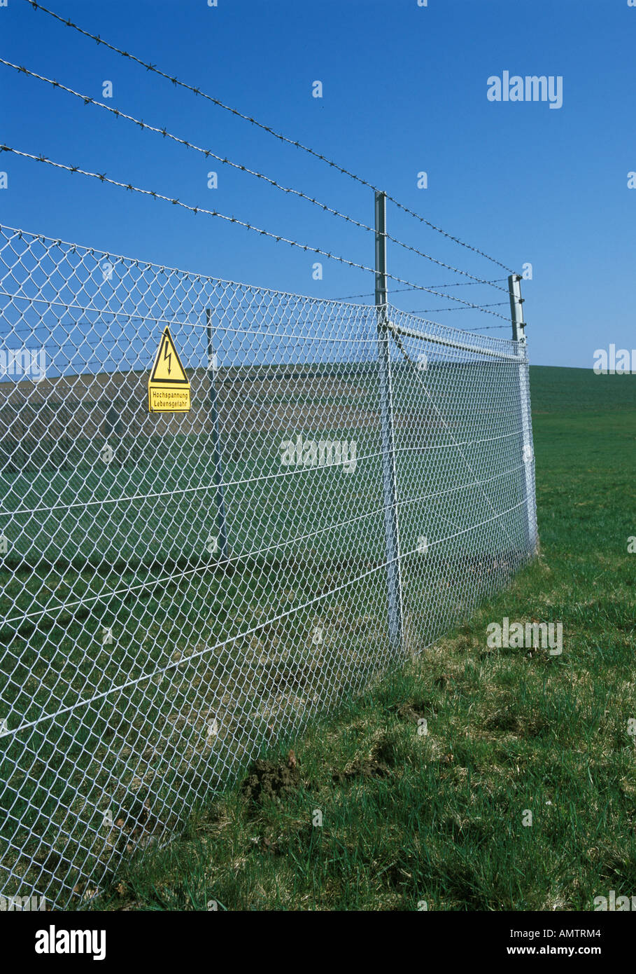 Fence with barb wire and high voltage wire Stock Photo Alamy
