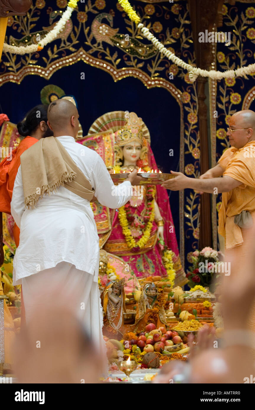 Hindu priest presenting offerings to the murtis during ceremony Stock Photo