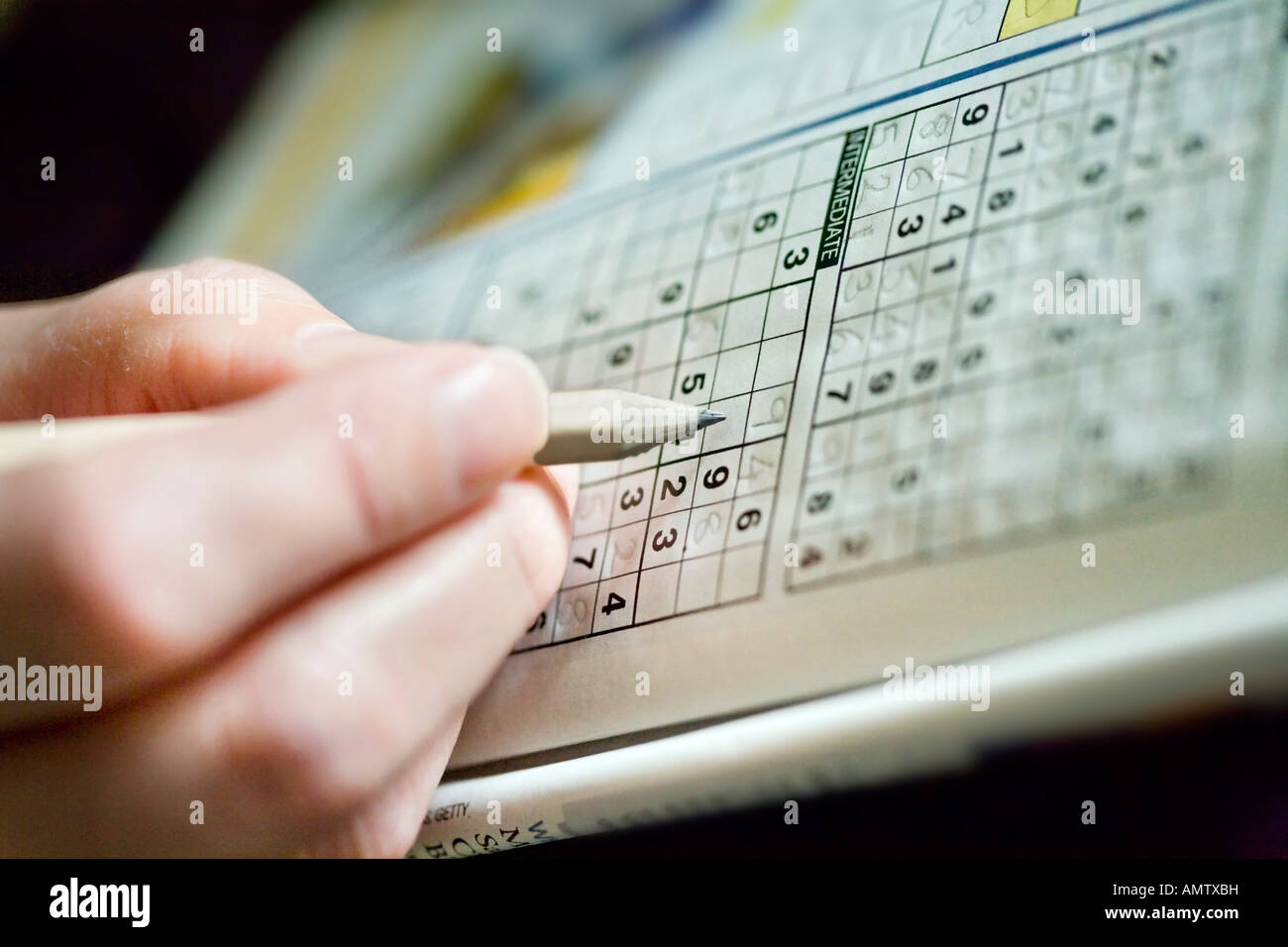 Close Up Of A Female Hand Holding A Pencil And Filling In A Sudoku 