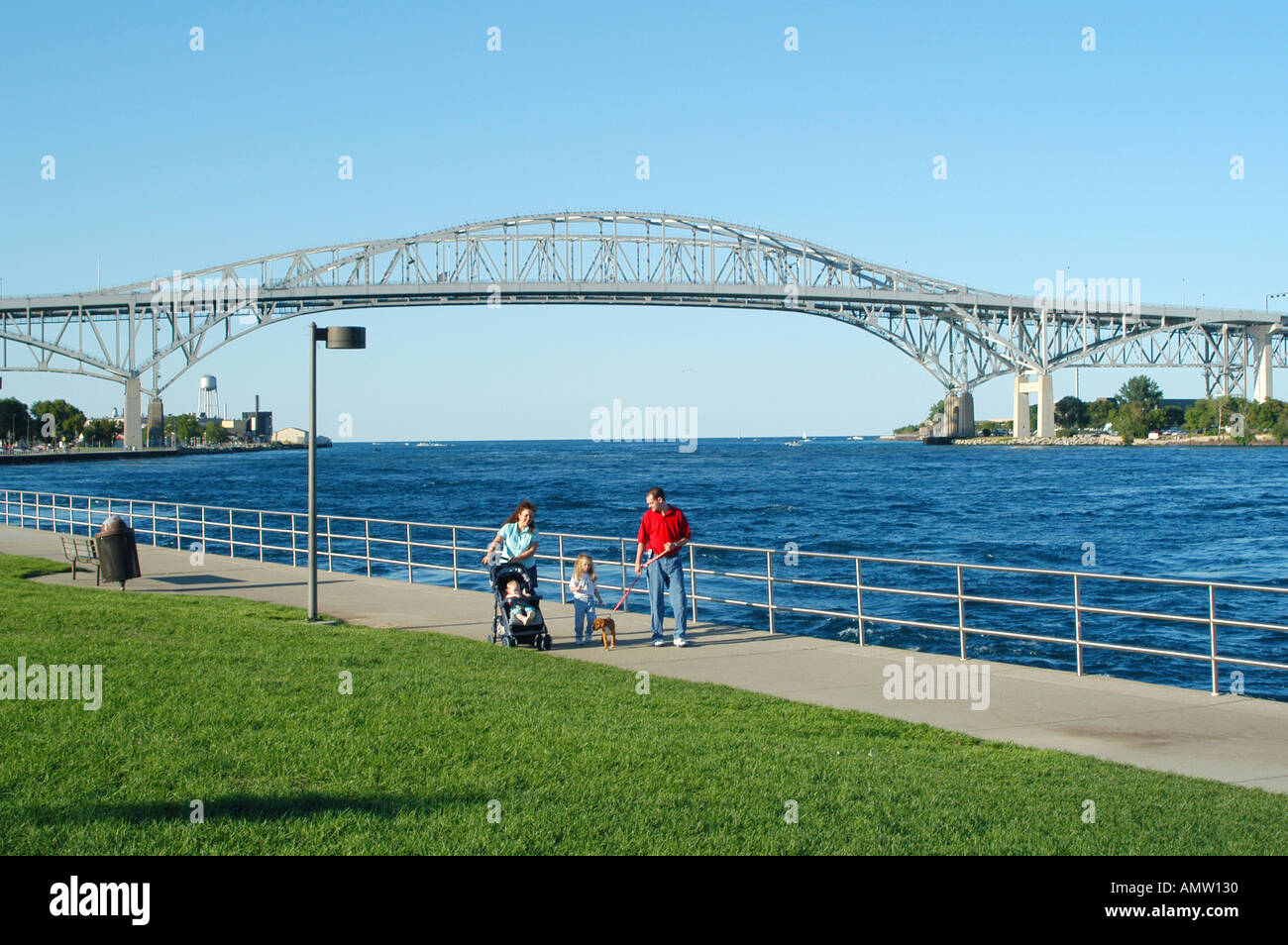 Family walks along boardwalk in front of the blue water international bridge at port huron Michigan Stock Photo