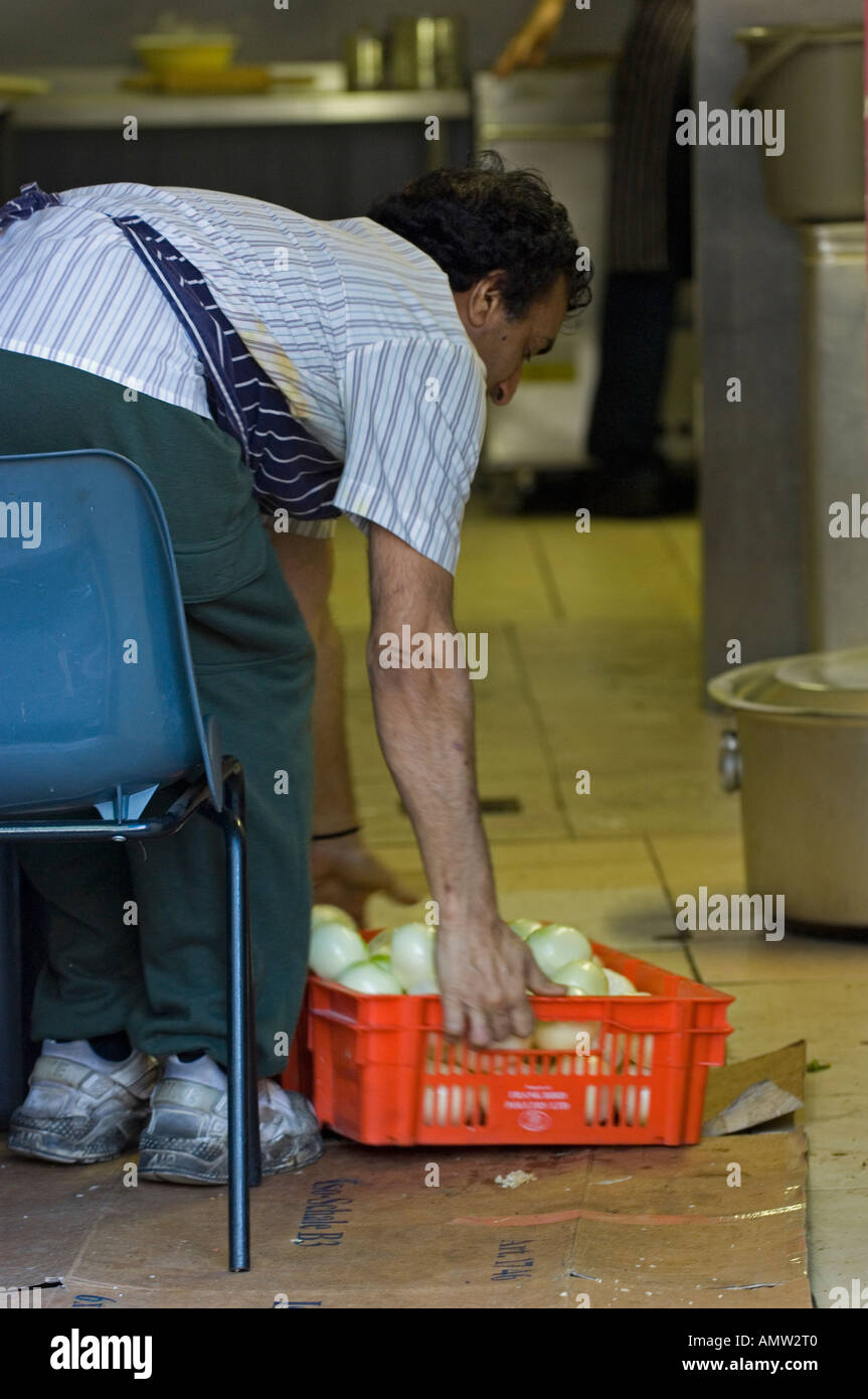Man moving a basket of vegetable in a restaurant kitchen Stock Photo