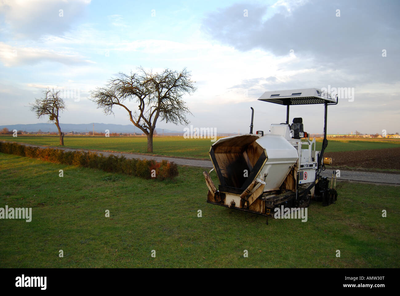 Small asphalt spreader waiting by the old used road in the countryside