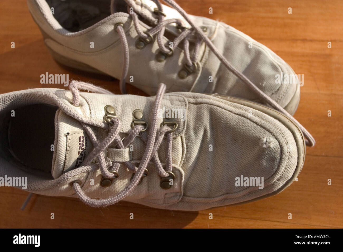 a pair of white tennis shoes with undone shoe laces sit next to each other Stock Photo