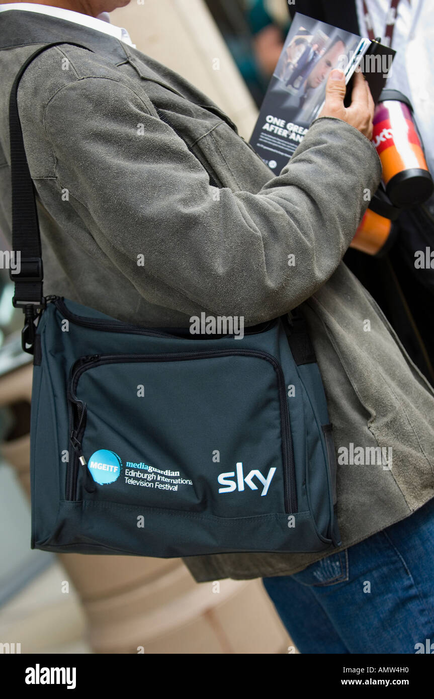 Man carrying a strap shoulder bag with the Sky televisionlogo Stock Photo