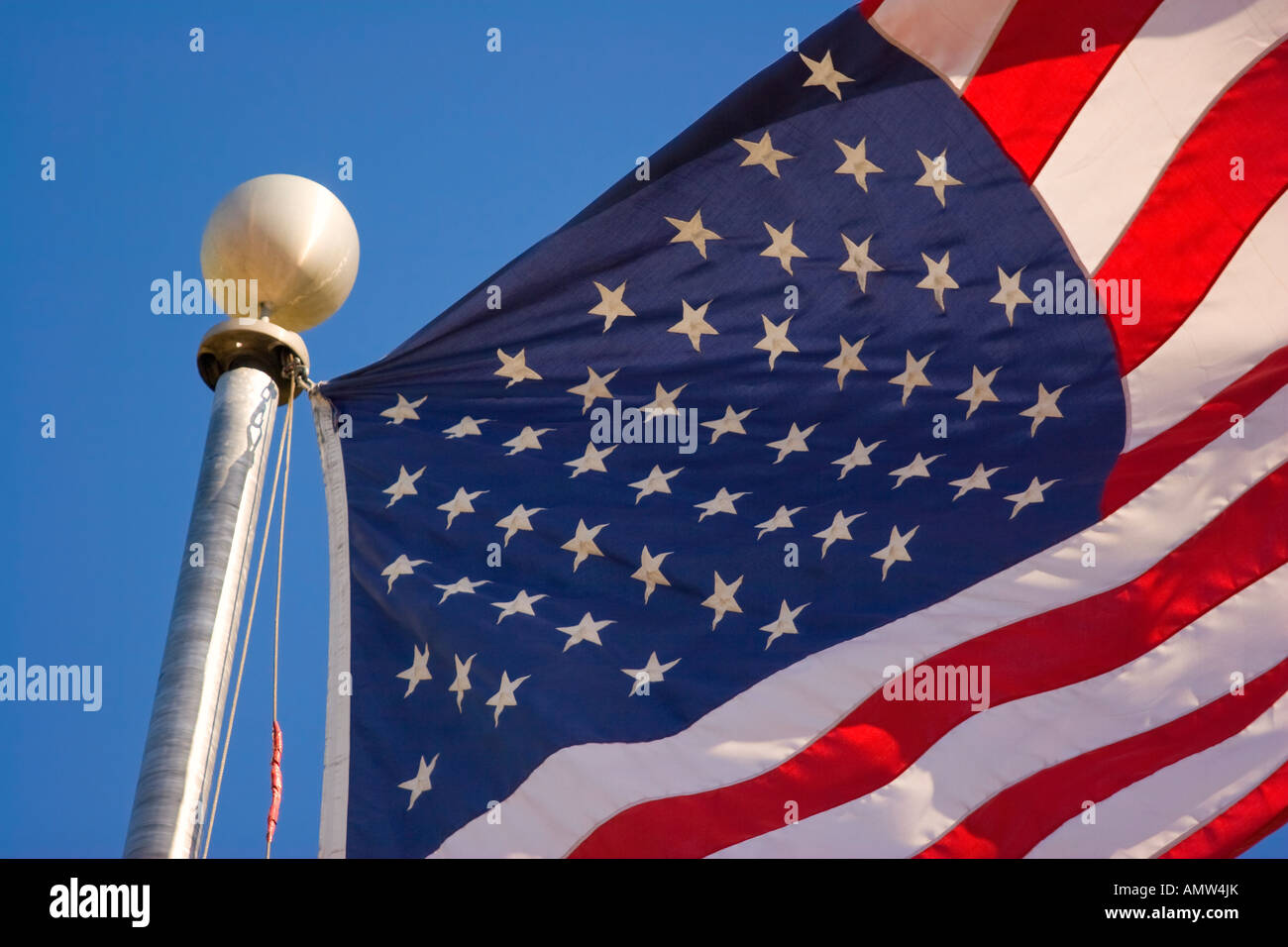American flag flying in the wind on flag pole against blue sky Stock ...