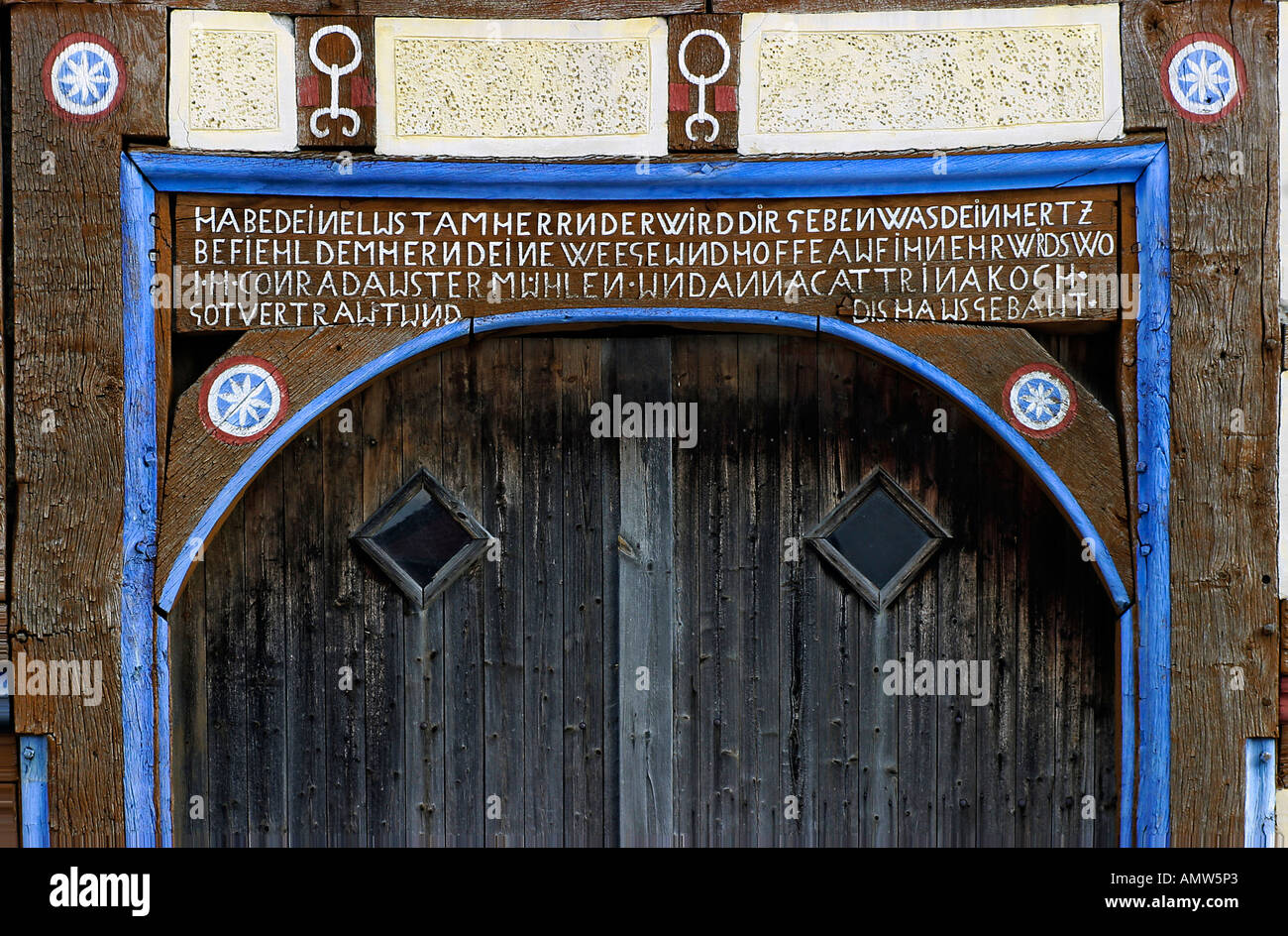 Ancient wooden barn-door with decorated door-arch and 'window-eyes'. Hessenpark, Neu-Anspach, Taunus, Hesse, Germany Stock Photo