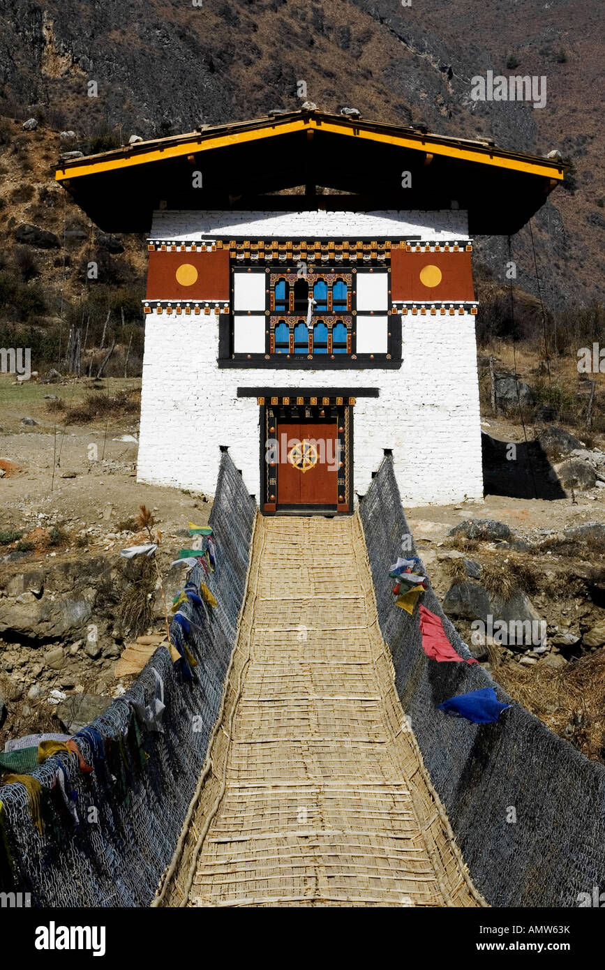 Traditional Bhutanese house with bridge and prayer flags. Painted on the door the Khorlo, the golden wheel of Buddha's doctrine Stock Photo