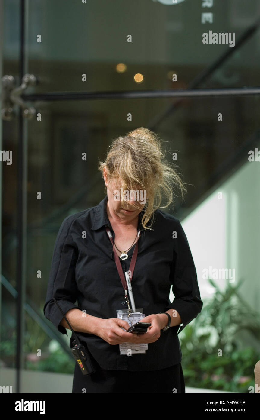 Woman wearing a badge writing a message on her mobile phone Stock Photo
