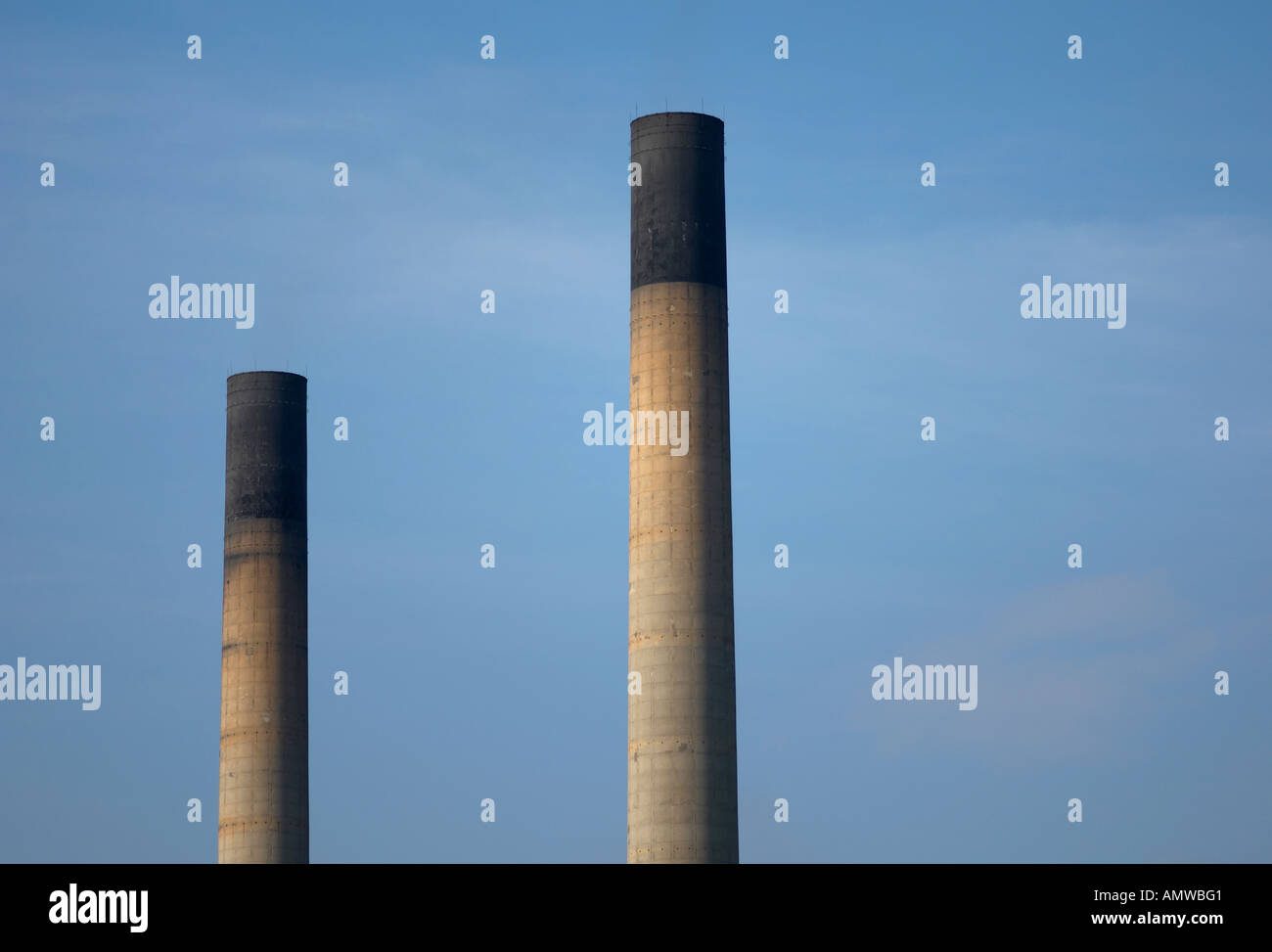 Industrial chimney stacks rising against a blue sky. Stock Photo