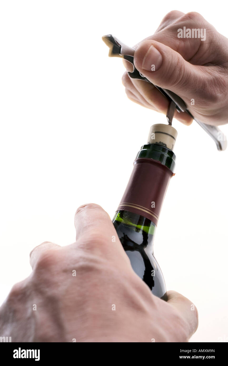 Close-up of person's hands opening bottle of wine with corkscrew Stock Photo