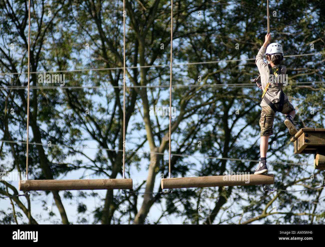 PICTURE CREDIT DOUG BLANE Boy crossing a log bridge at the Aerial Extreme Willen Lake Milton Keynes City of Milton Keynes Stock Photo