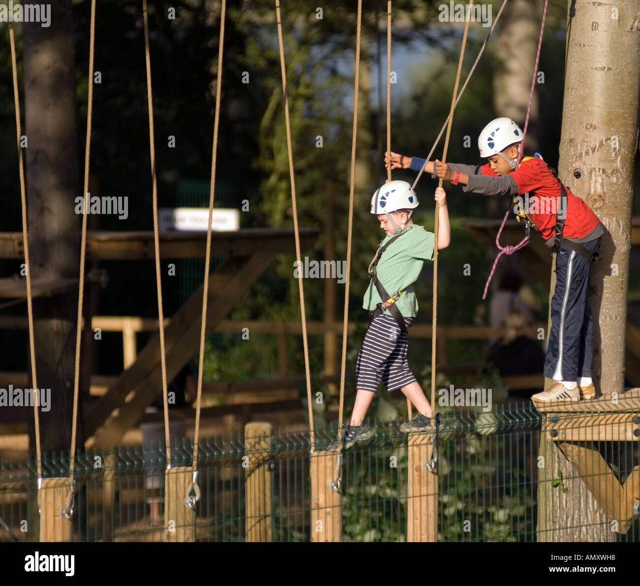 PICTURE CREDIT DOUG BLANE Young boy being helped across a log bridge at the Aerial Extreme Willen Lake Milton Keynes City of Mil Stock Photo