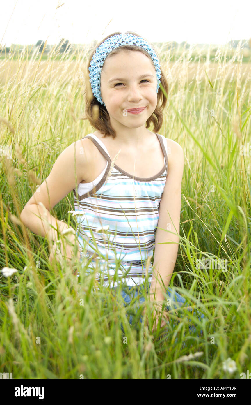 Portrait of girl sitting in field and smiling Stock Photo - Alamy