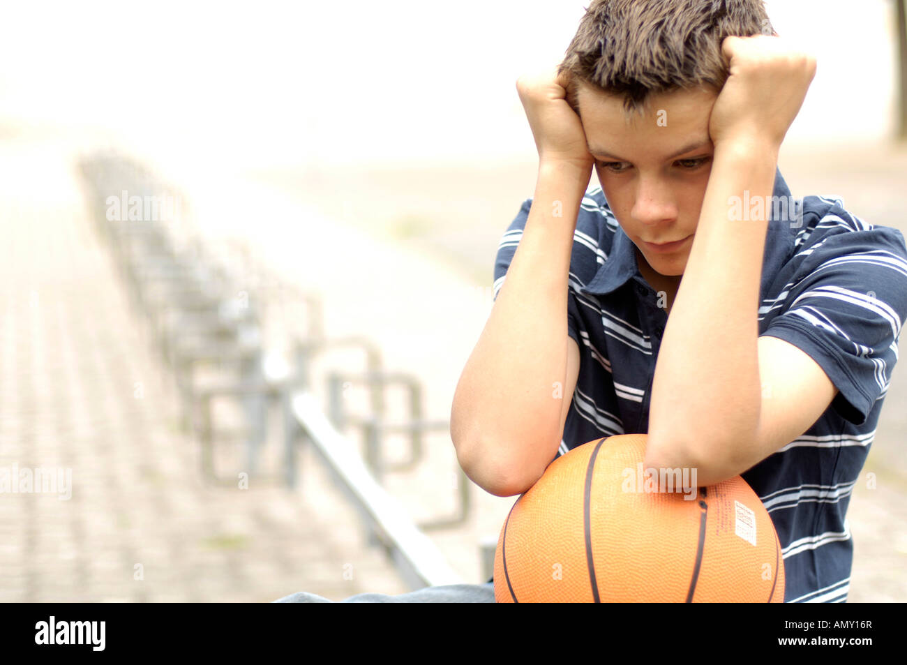 Close-up of teenage boy looking serious and holding basketball Stock Photo