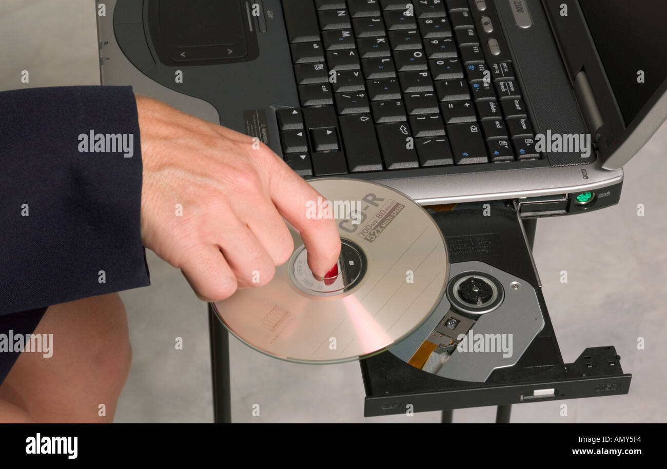 Caucasian woman’s hand inserting a CD into laptop computer, USA Stock Photo