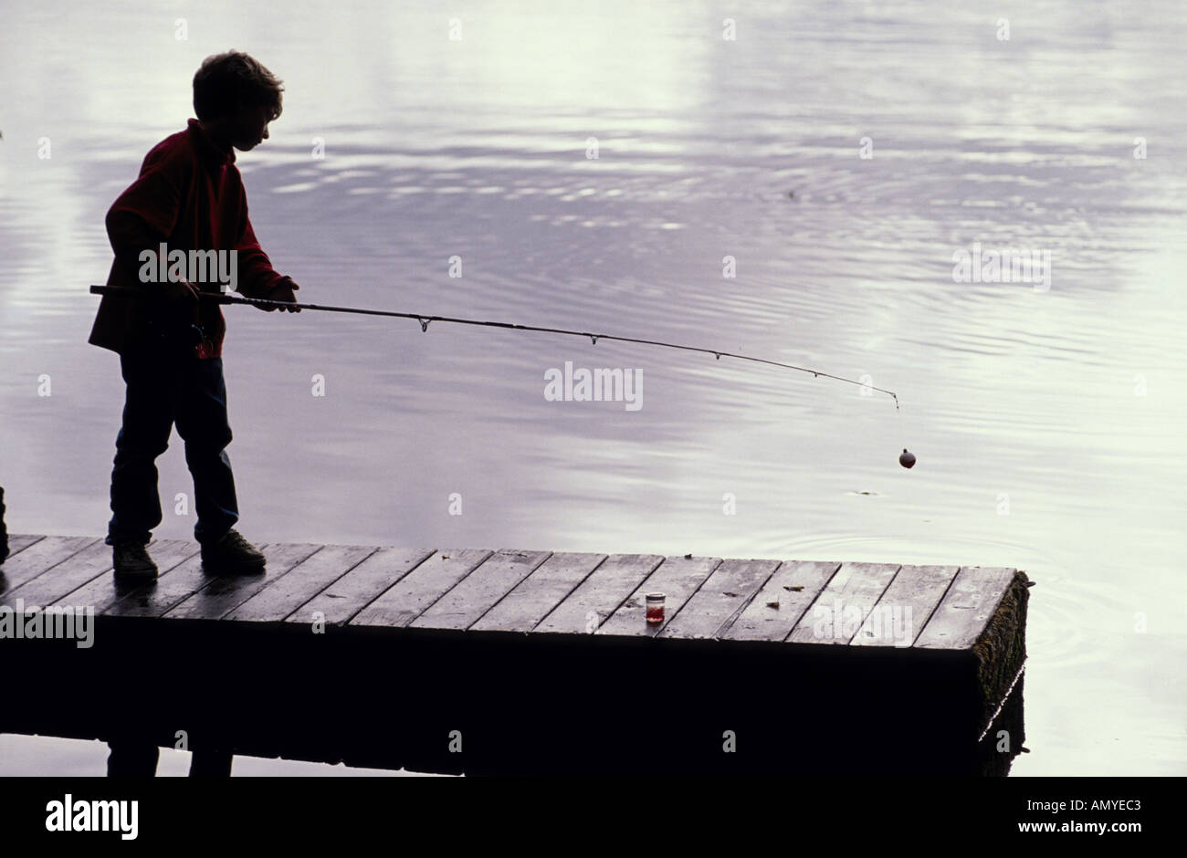 Silhouette boy fishing from dock hi-res stock photography and