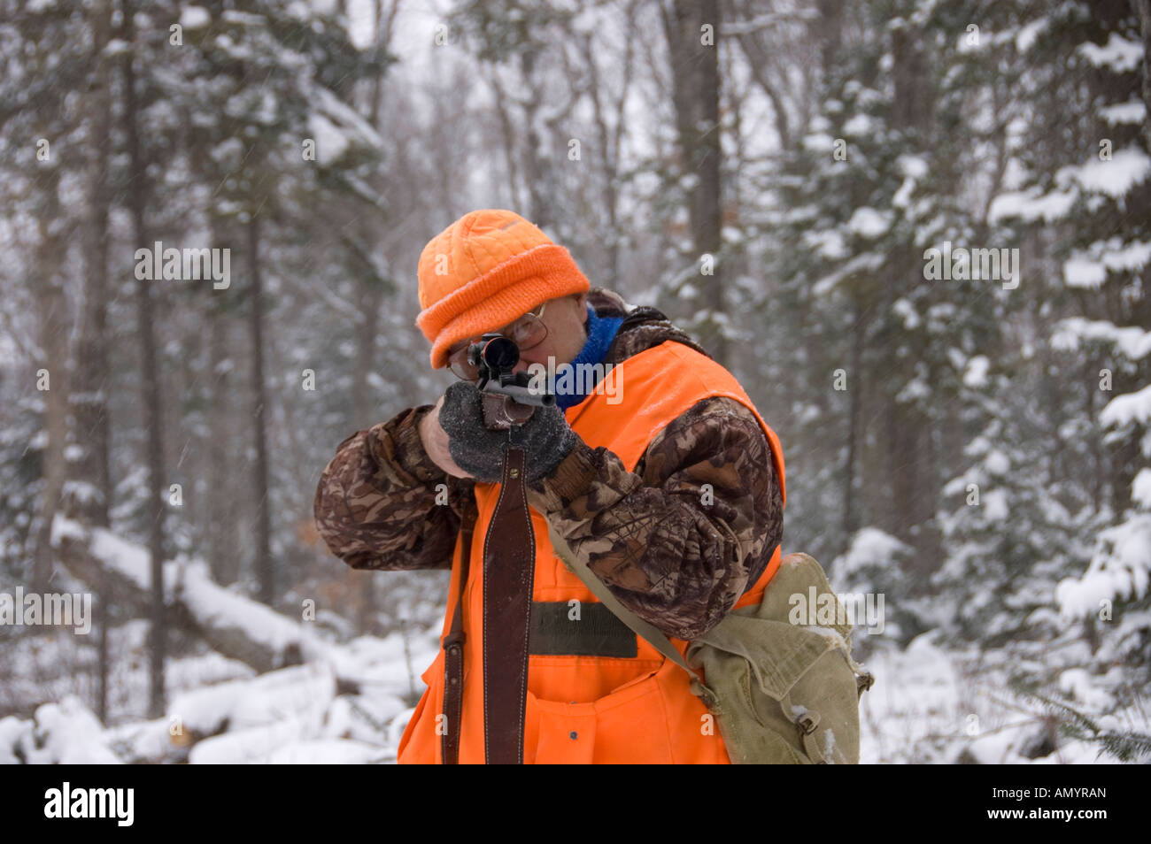 Senior hunter aiming a deer in his sight under the snow Quebec Canada Stock Photo