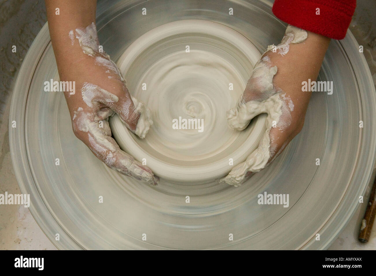 7-10 year old child throws a pot on the potters wheel Stock Photo