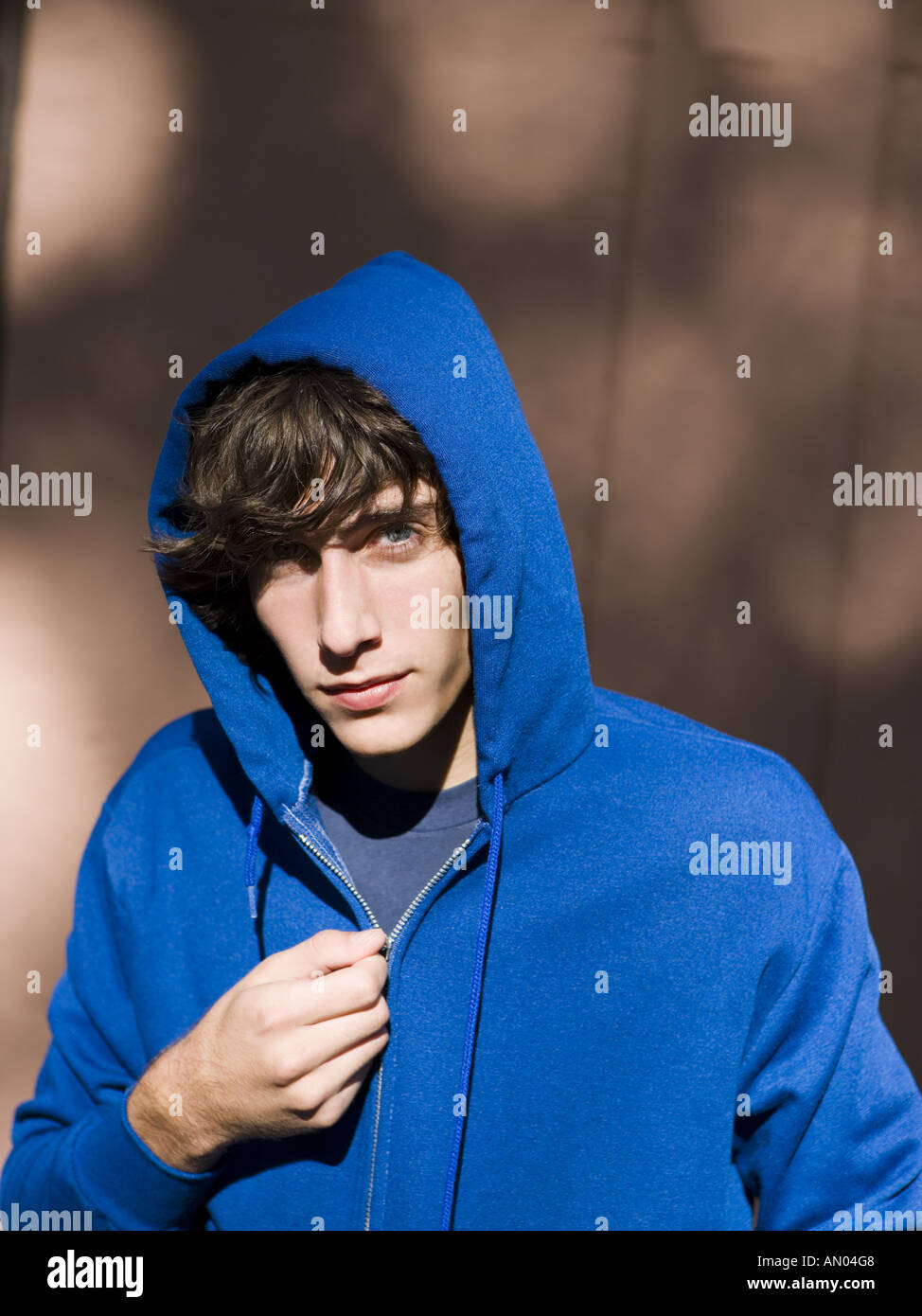 Portrait of a teenage boy zipping his hooded shirt Stock Photo
