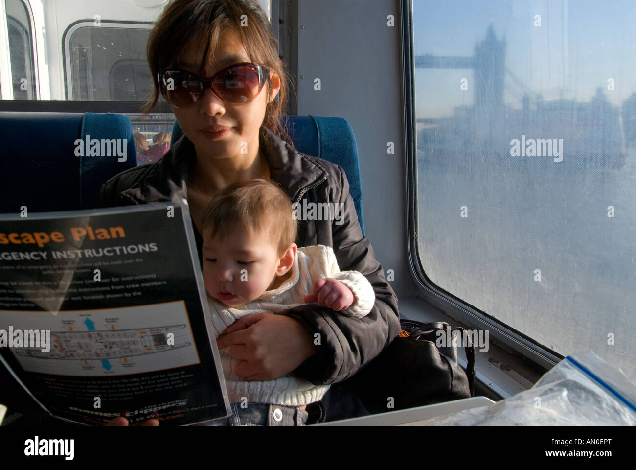 Korean Asian mother and baby reading safety instructions on Thames Clipper passenger service London Stock Photo