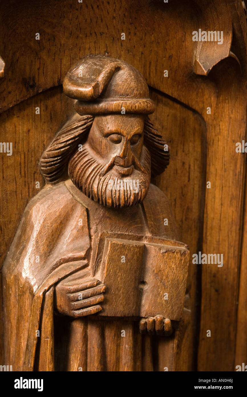 UK Suffolk Blythburgh village All Saints Church Priests Stall front Saint Luke with doctors cap and book Stock Photo