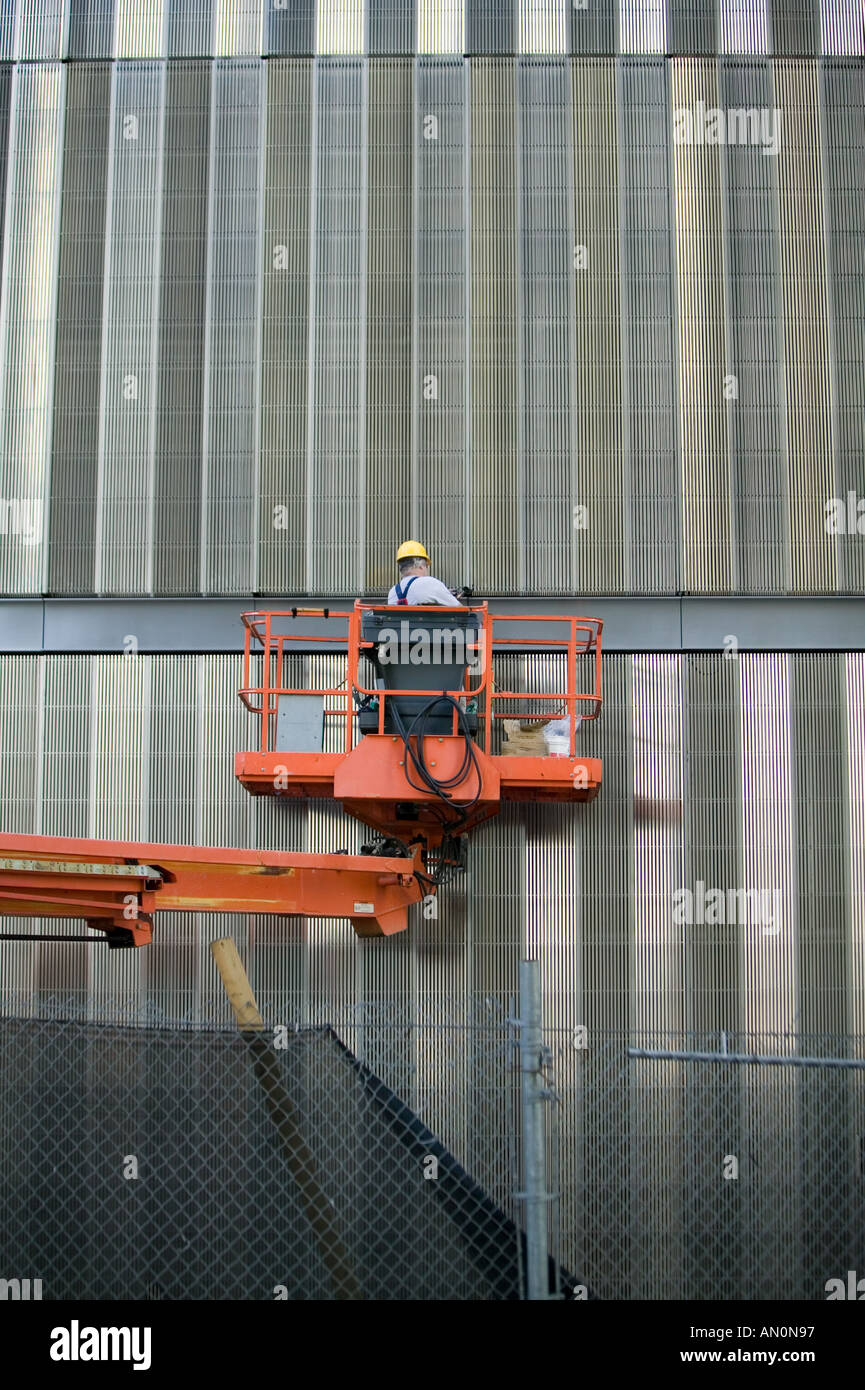 Construction worker wearing a yellow hat stands on an orange elevated