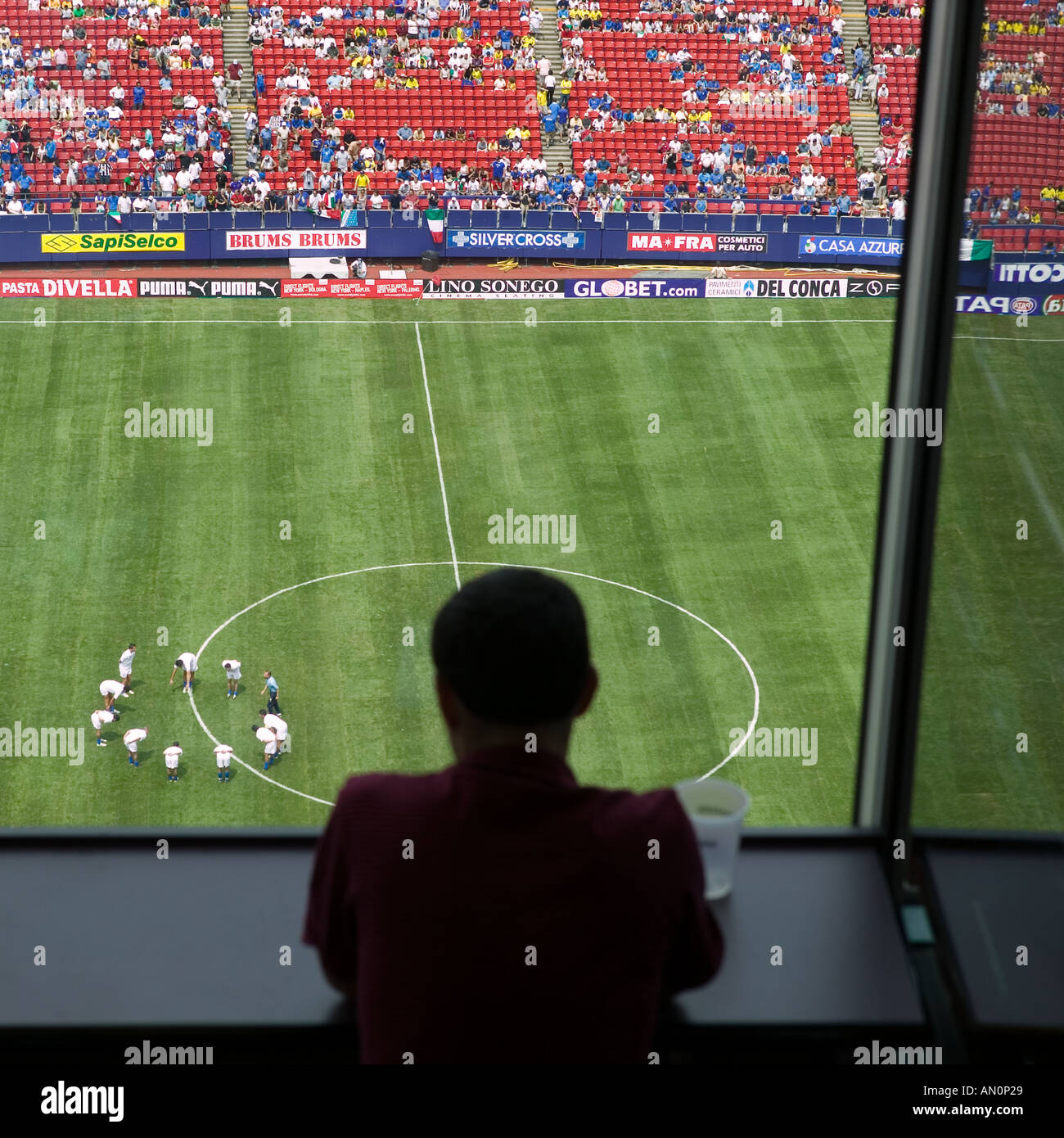 A journalist watches football players warm up on the field from the press box of the stadium June 05 Stock Photo