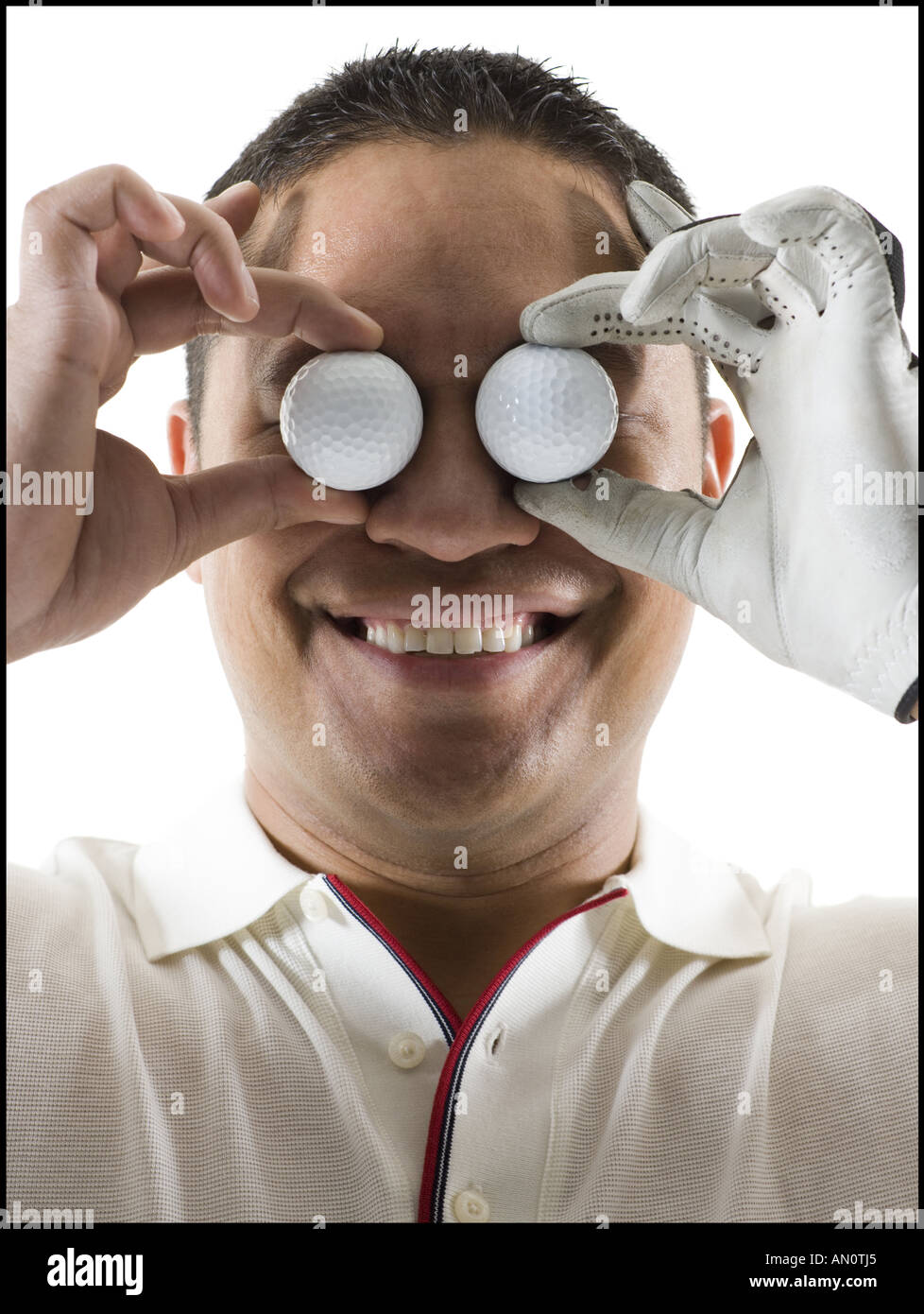 Close up of a mid adult man holding two golf balls in front of his eyes Stock Photo