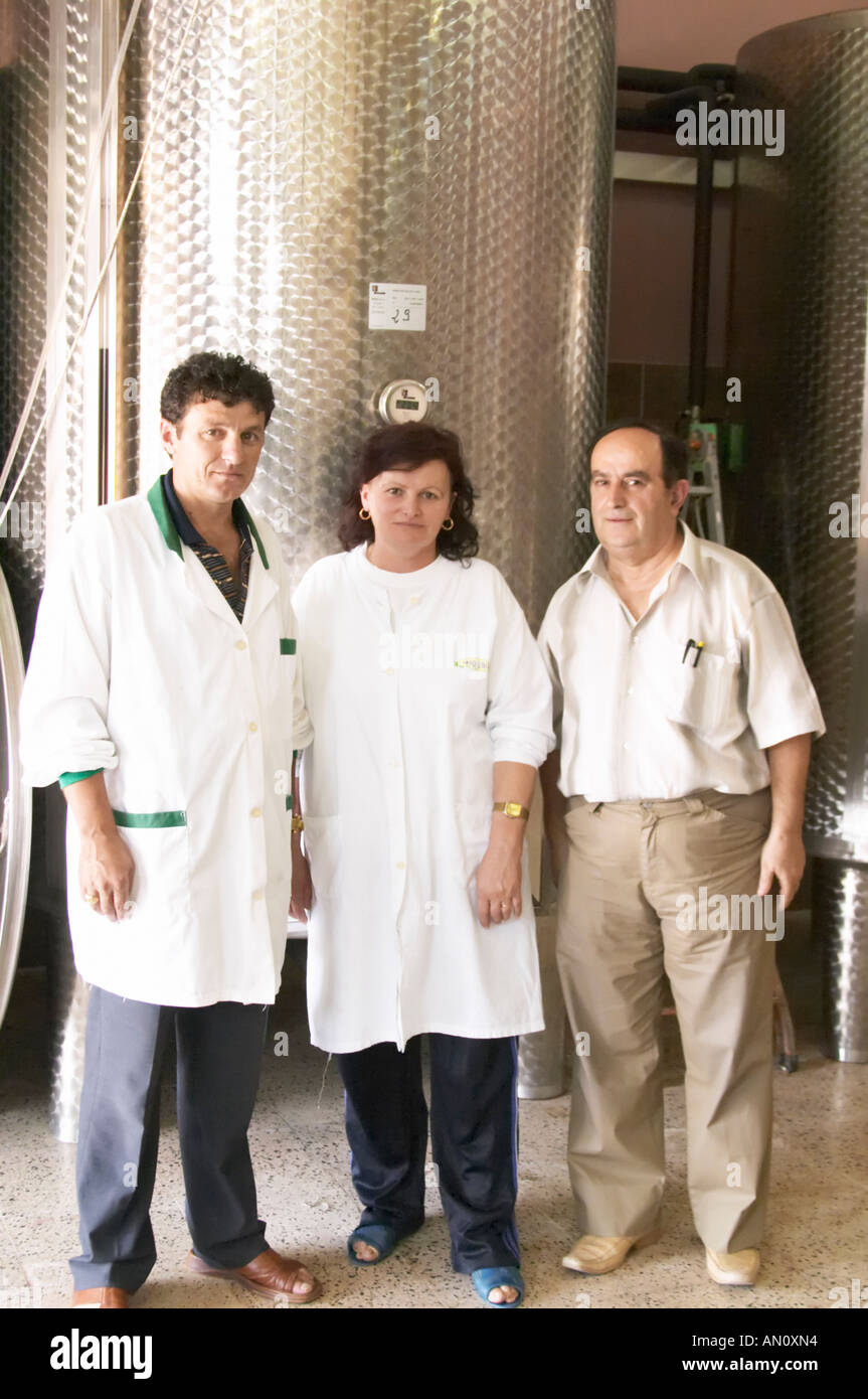 Enver Ulqini, oenologist and winemaker in front of a stainless steel fermentation tank together with two winery workers. Kantina Miqesia or Medaur winery, Koplik. Albania, Balkan, Europe. Stock Photo
