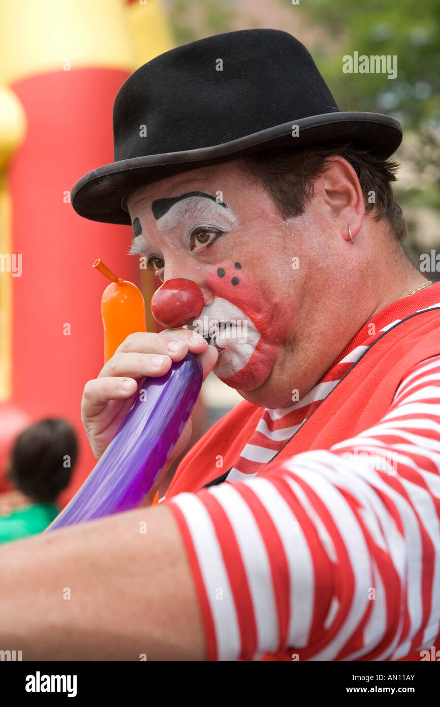 Clown blows up balloons for children Stock Photo