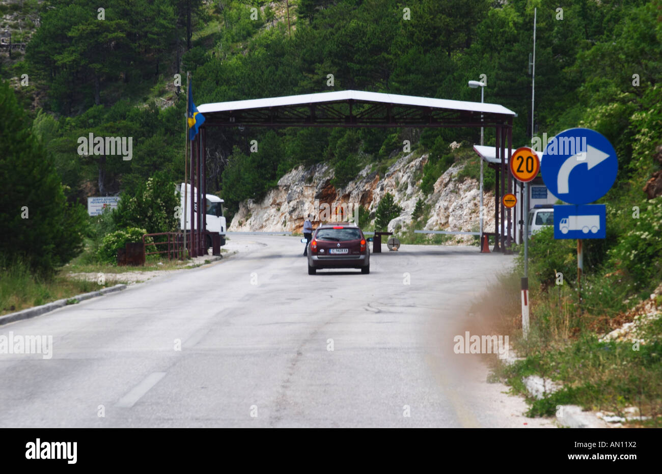 The border crossing between Montenegro and Bosnia-Herzegovina. A car approaching the border control checkpoint where a guard is Stock Photo