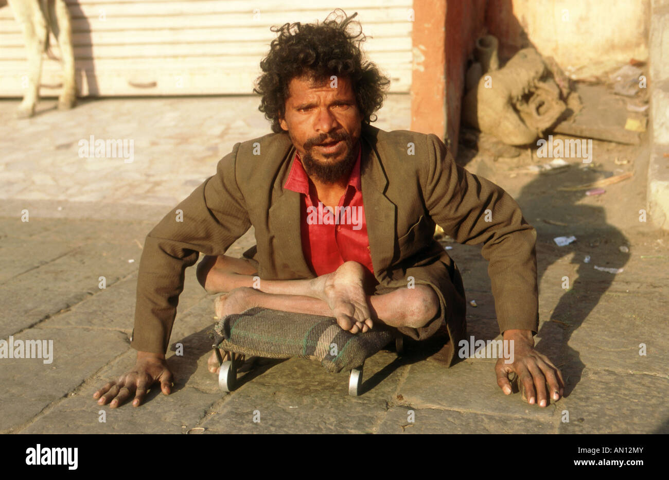 Man with no use of his legs pushing himself along the street using his