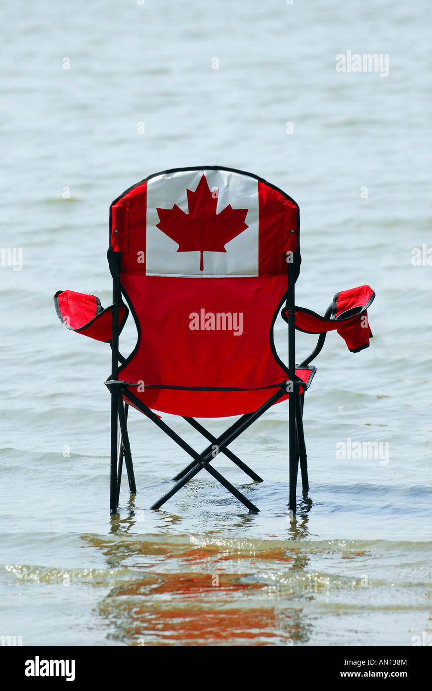 Folding chair with canadian flag design in shallow lake water Stock Photo