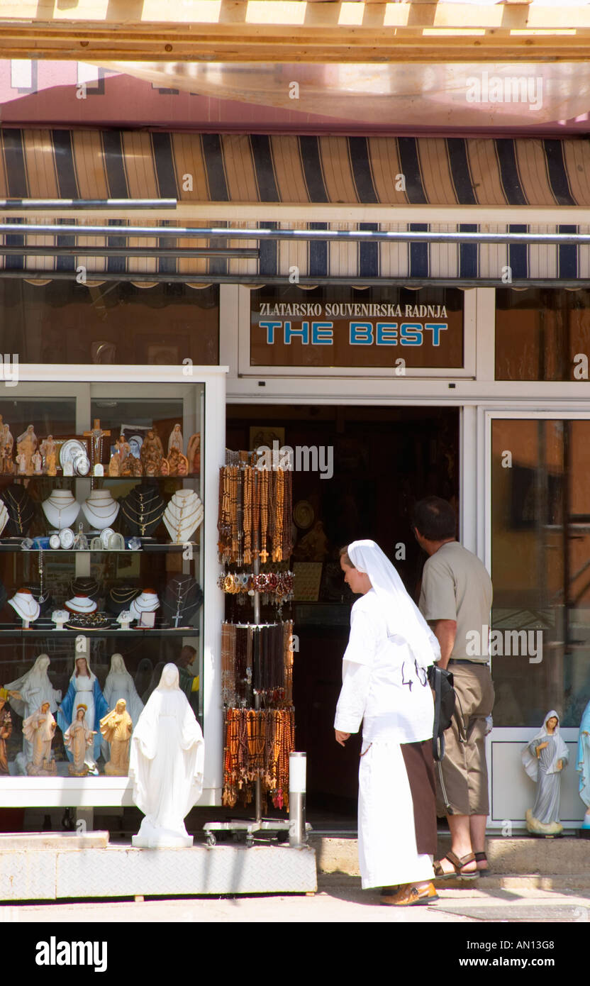 A shop with souvenirs for pilgrims, called 'The Best'. A nun in white looking at the things for sale. Madonna statue, rosary beads. Medugorje pilgrimage village, near Mostar. Medjugorje. Federation Bosne i Hercegovine. Bosnia Herzegovina, Europe. Stock Photo