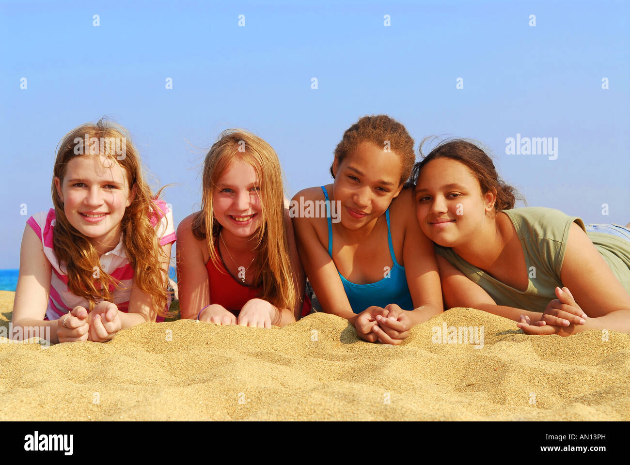Portrait of four smiling teenage girls on a sandy beach Stock Photo - Alamy