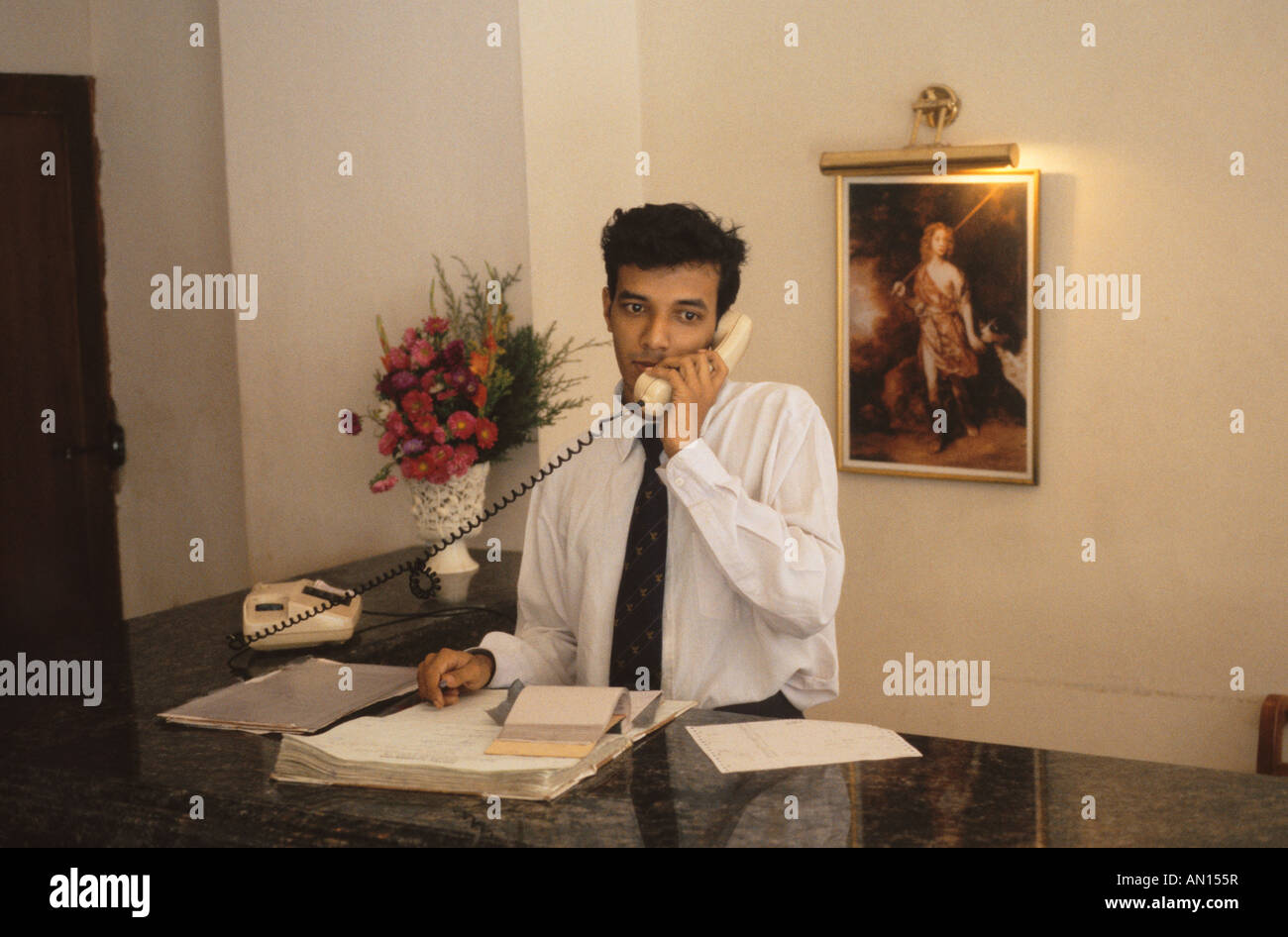 Hotel receptionist talking on telephone hires stock photography and