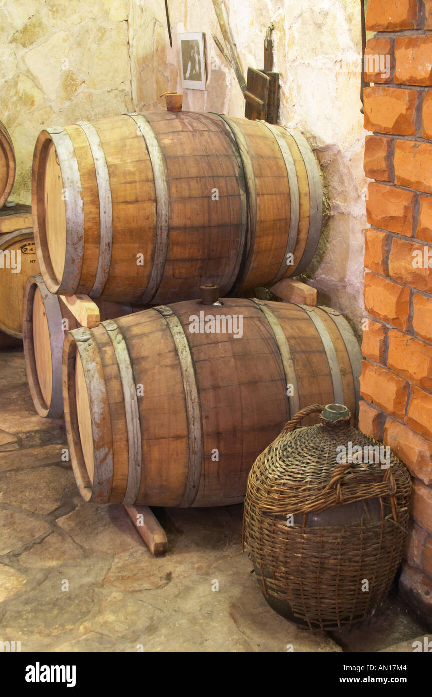 Old oak barrels and an old demijohn in a wicker basket in the wine