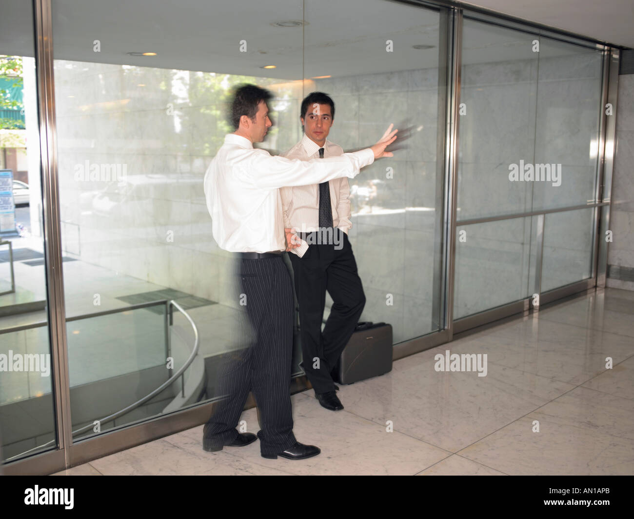 Men conferring in front of a glass window Stock Photo