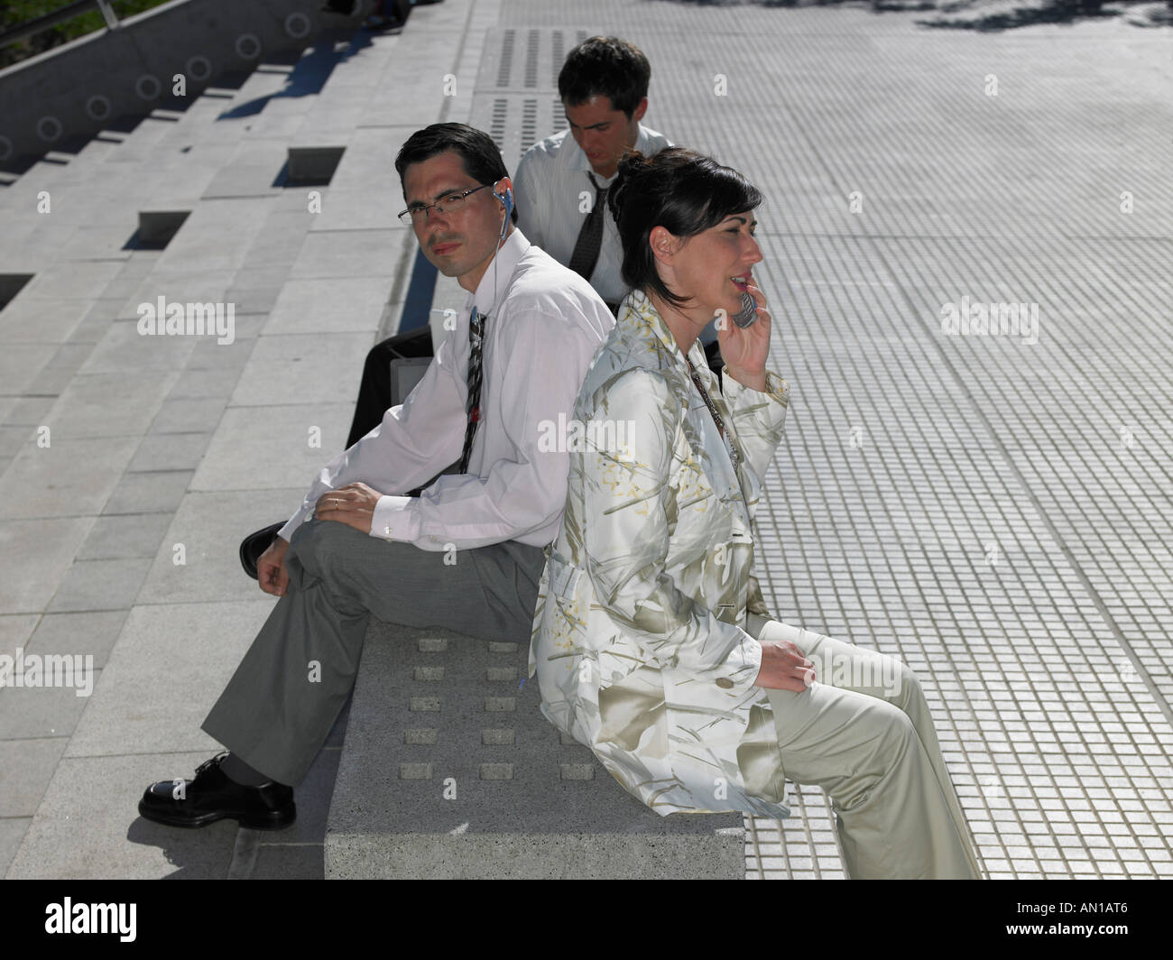 Three people sitting on a stone bench Stock Photo