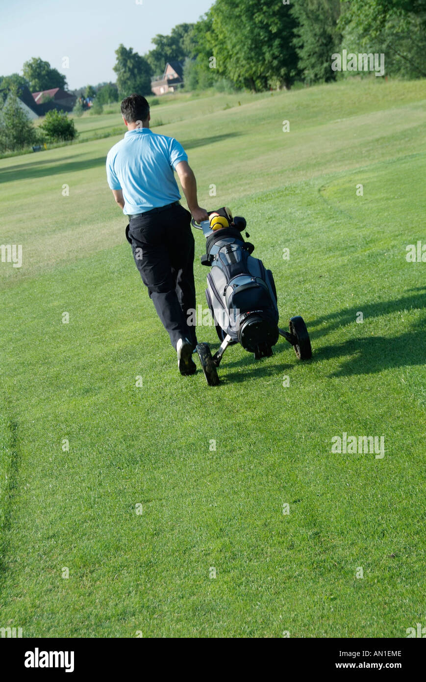Golf Golfing Golfsport, a golf player carrying his trolley on fairway Stock Photo