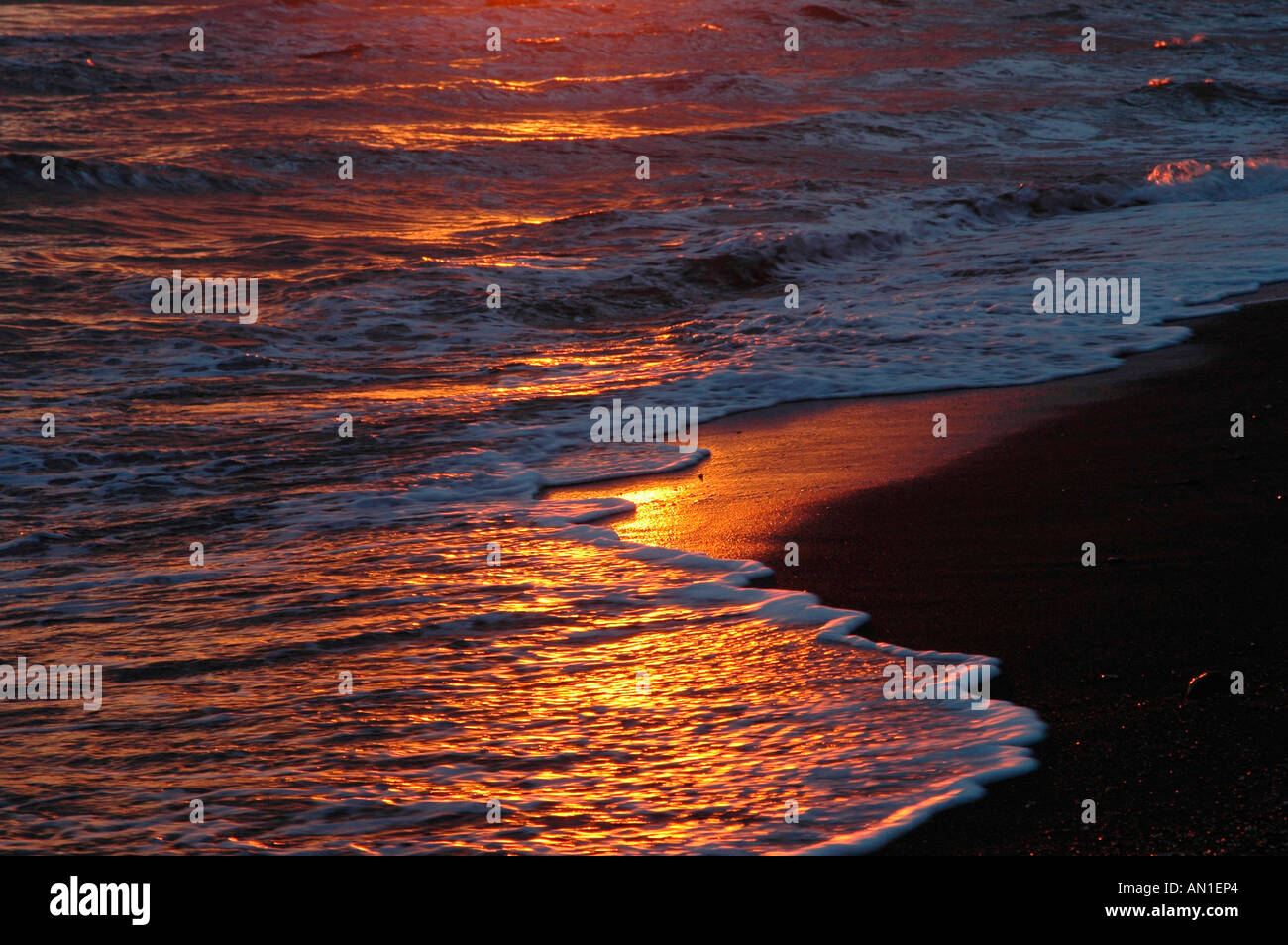Golden sunset reflects on waves and beach Stock Photo - Alamy