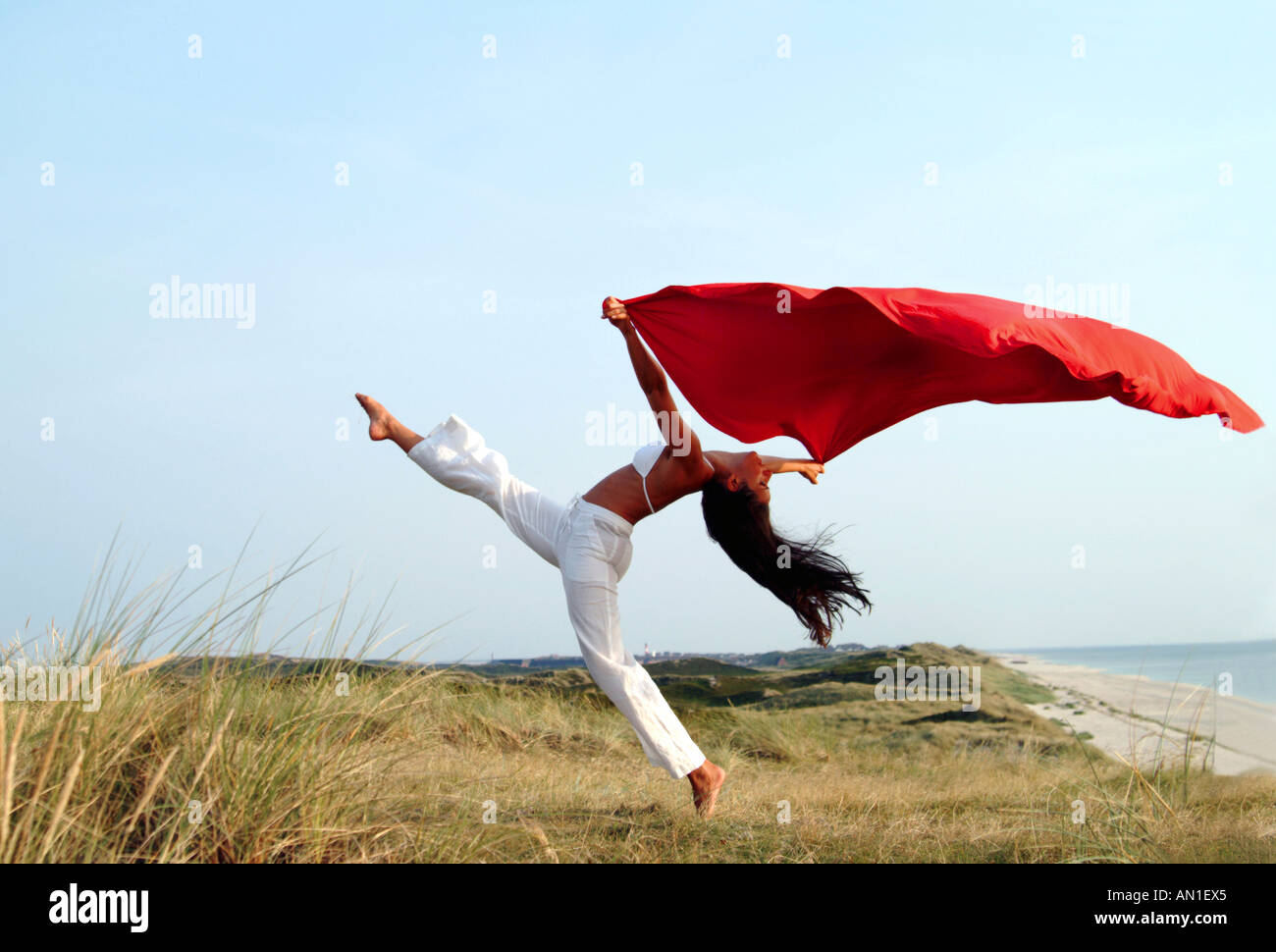 young woman feeling free with a red towel at sea, vitality, happiness, delight, well being Stock Photo