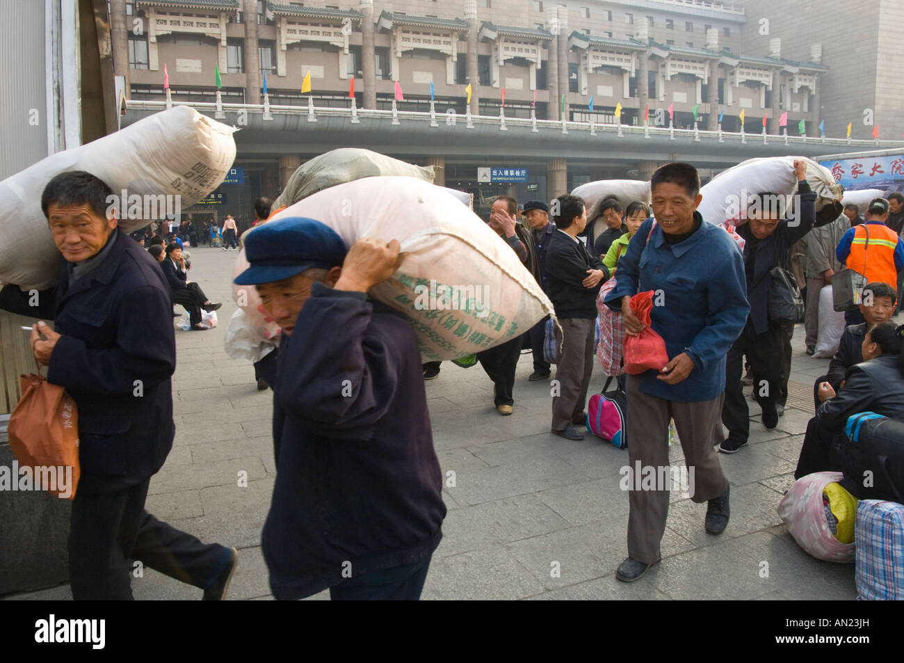 China beijing Fengtai Beijing West railway Station Front courtyard group of men carrying bulky bags with atation in bkgd Stock Photo