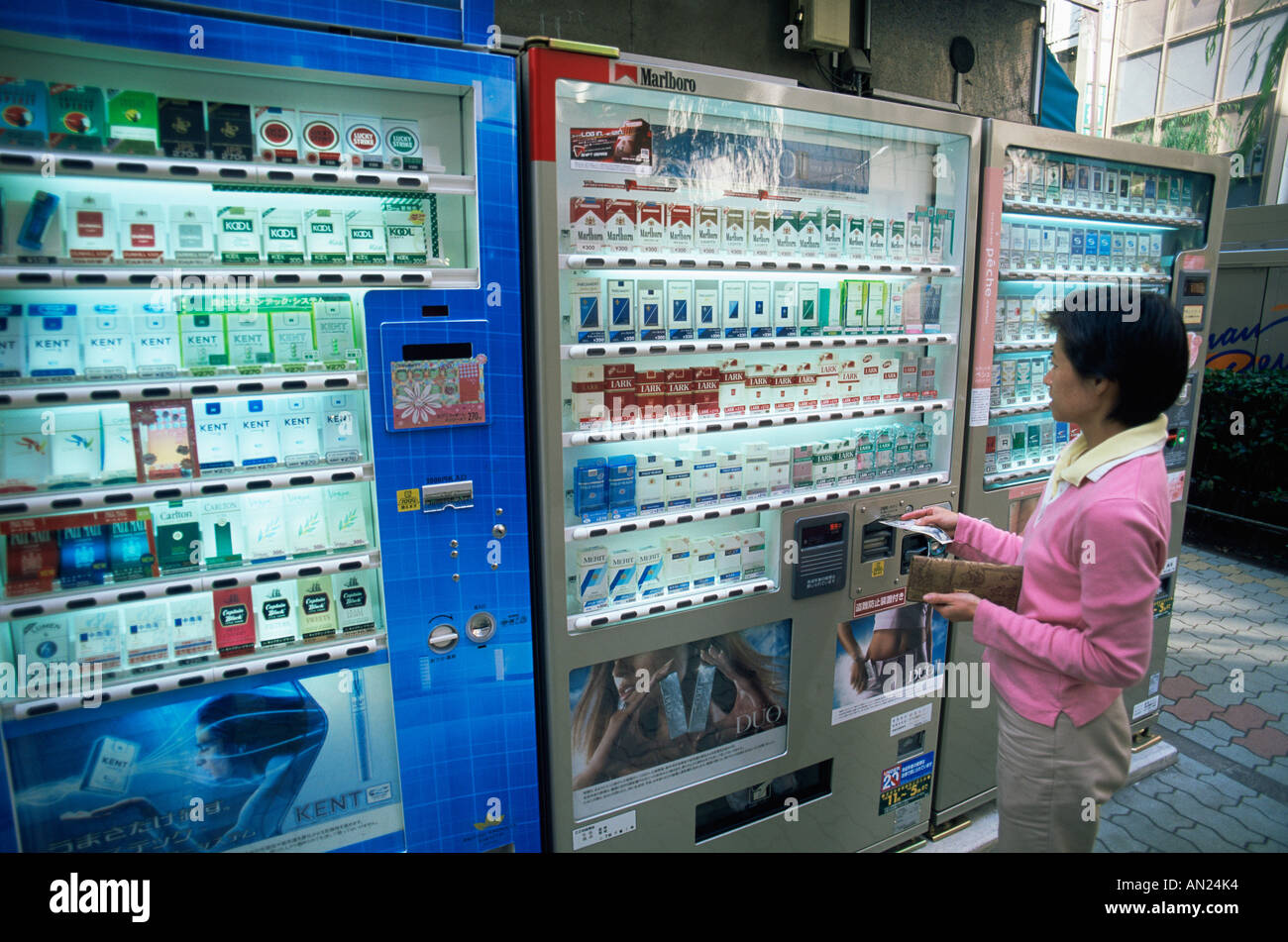 Japan, Honshu, Tokyo, Woman Buying Cigarettes from Vending Machine