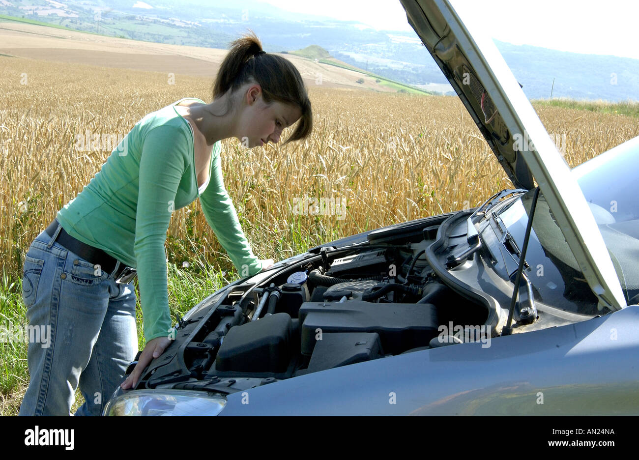 Young woman looking under the bonnet hood of her car which has broken down Stock Photo