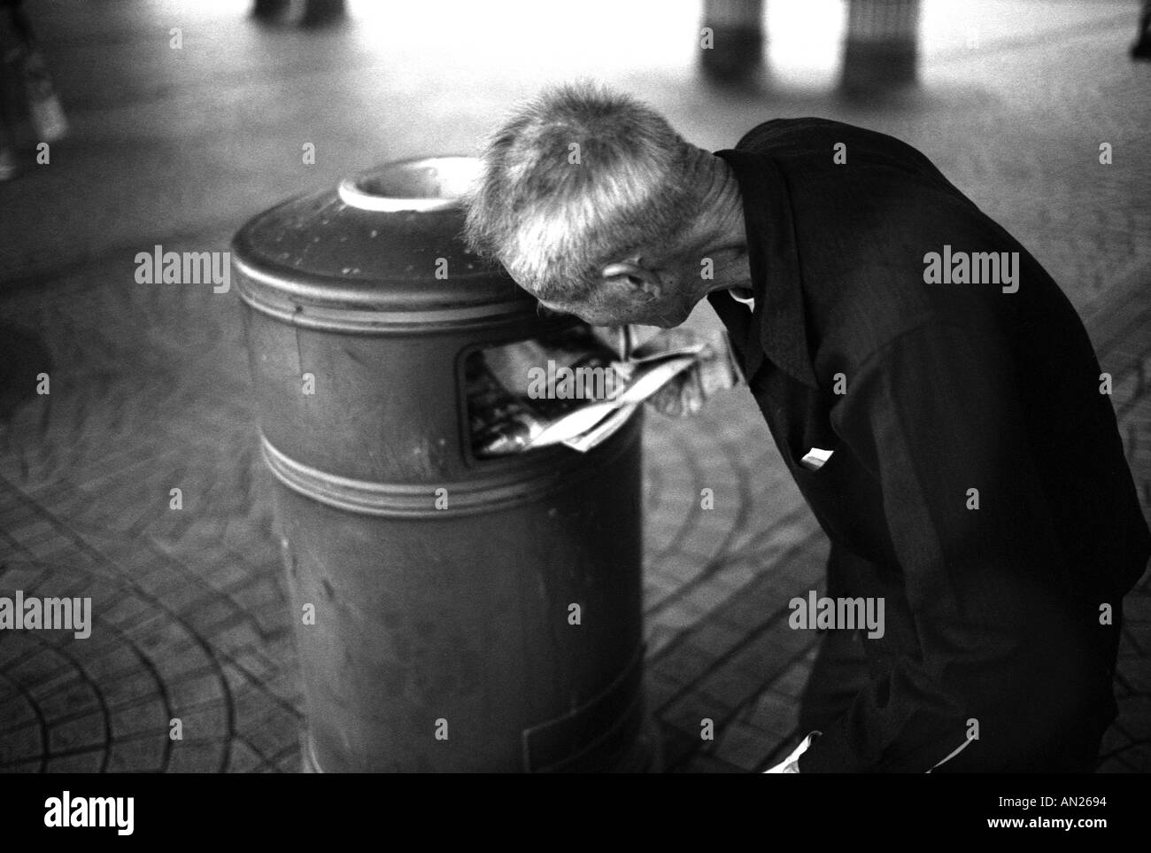 Homeless man searches through rubbish bin looking for anything to recycle to make money Tsim Sha Tsui Hong kong Stock Photo
