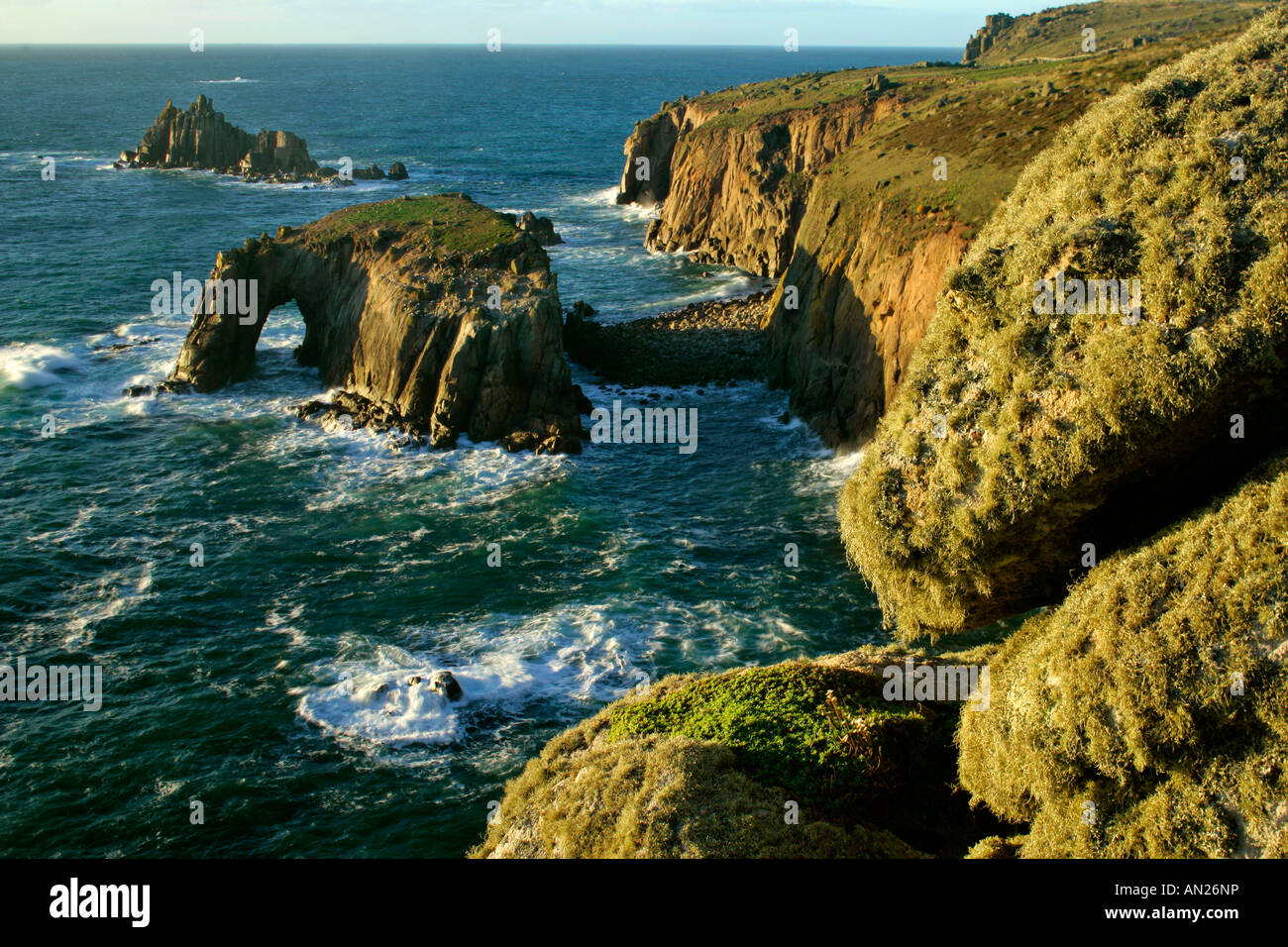 rugged coastline with rock arch in evening light Lands End Cornwall