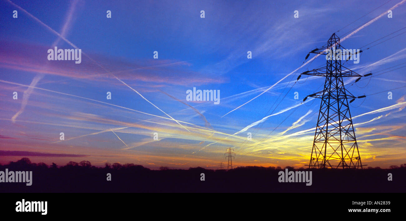 vapour trails in early morning sky and pylon silhouette. Stock Photo